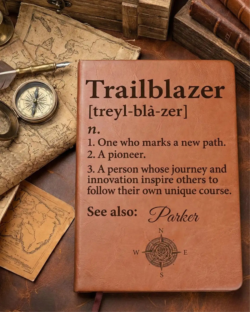 Brown leather-bound notebook with engraved definition of ’trailblazer’ and a compass rose design at the bottom.