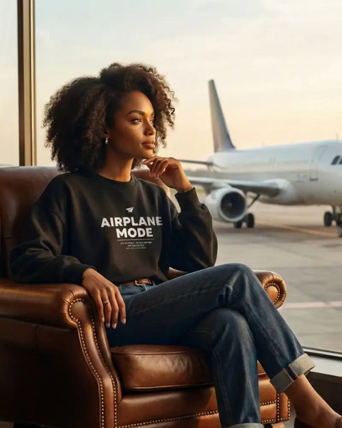 Unisex black airplane mode crewneck sweatshirt in leather armchair
