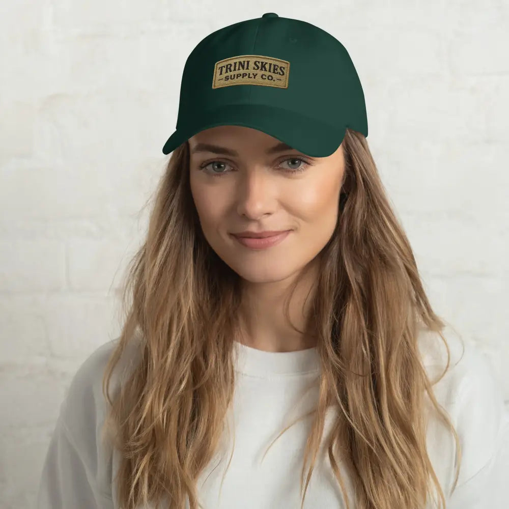 Trini Skies Heritage Patch Hat woman in dark green cap with tan patch