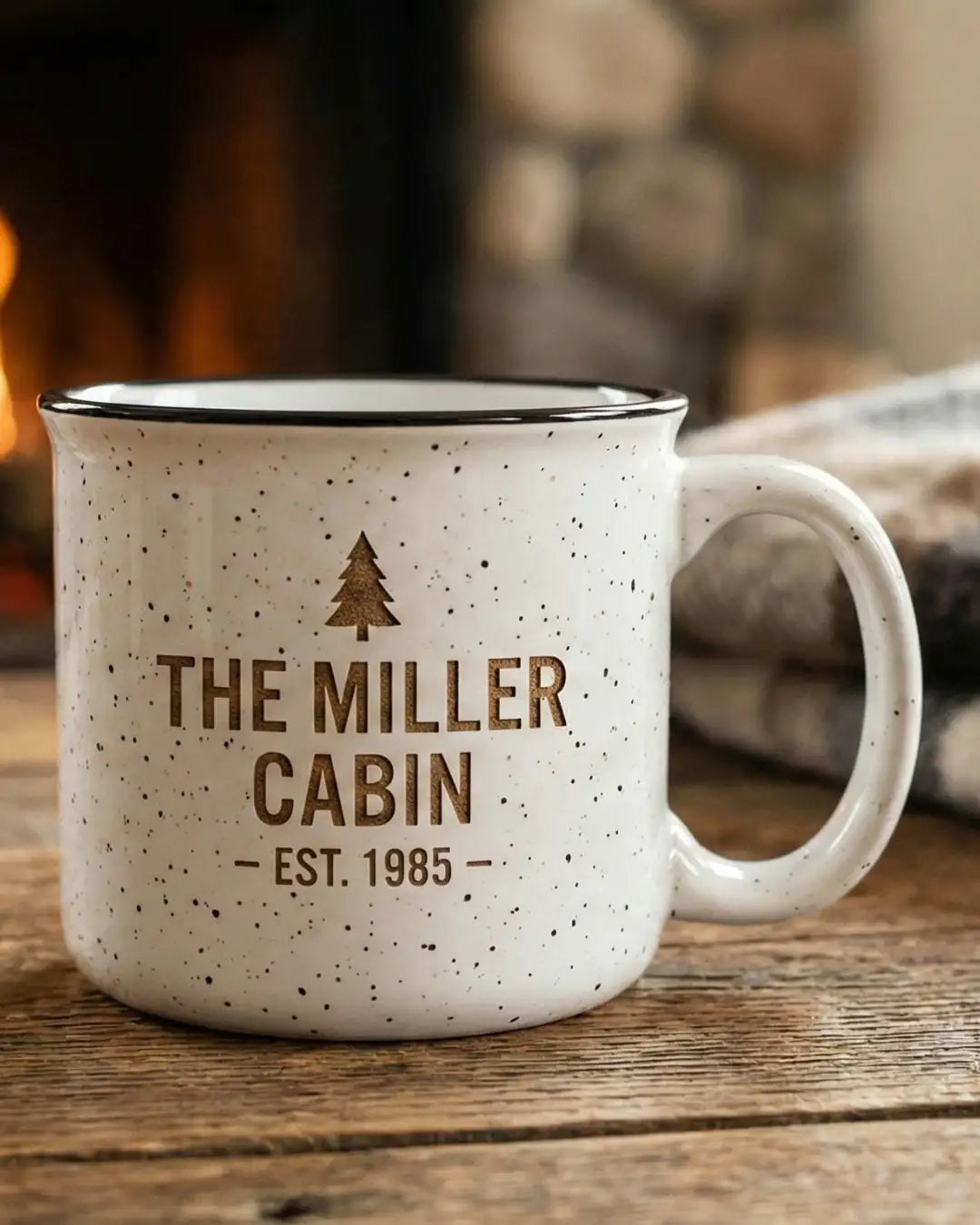 White speckled enamel camp mug with brown engraved text reading ’the miller cabin — est.
